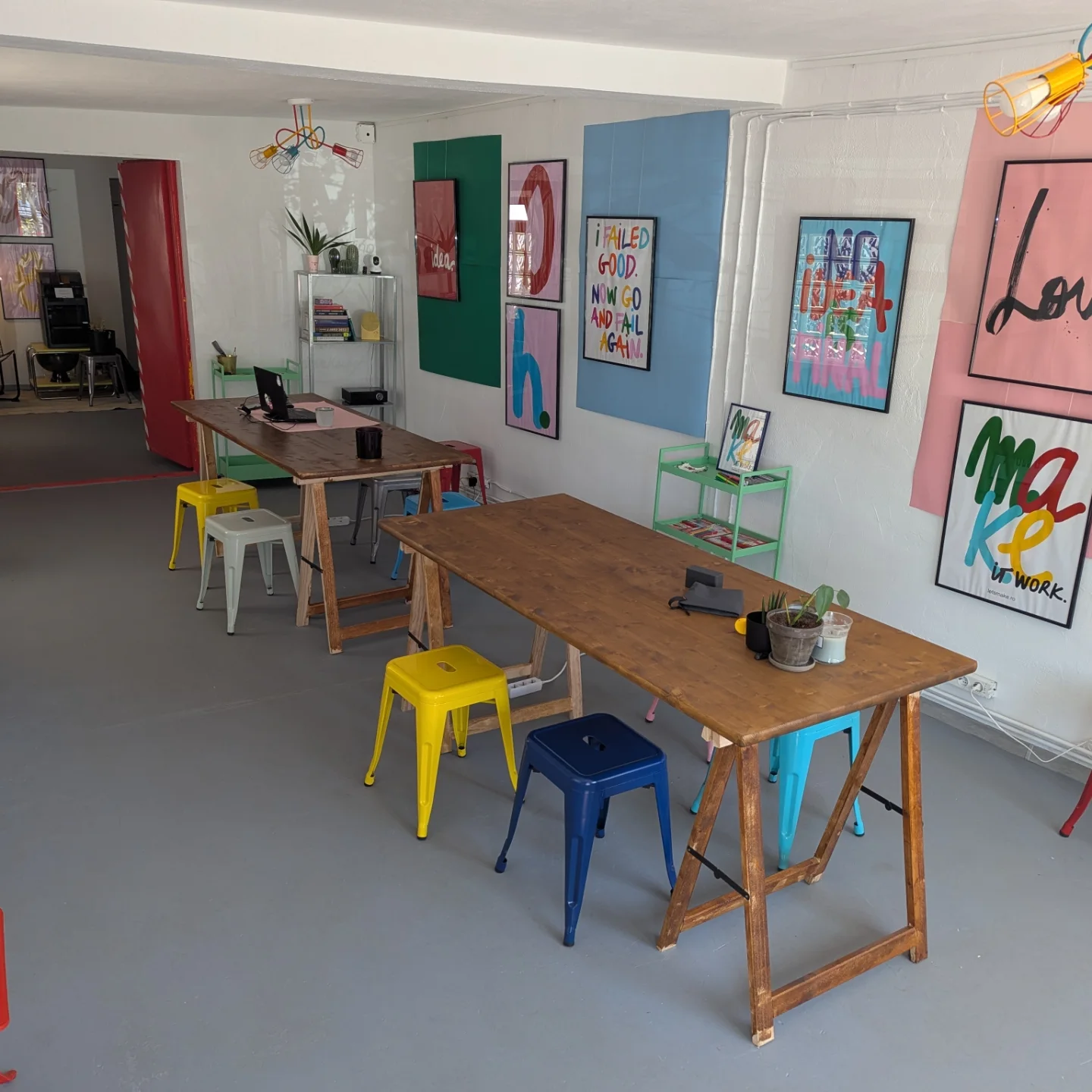 Wooden tables and stools in front of a wall of colourful posters